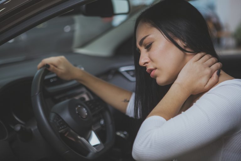 Female driver rubbing her aching neck after accident